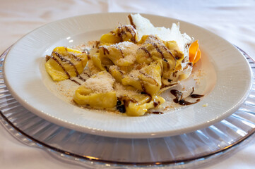 Italian food, fresh home made pumpkin stuffed pasta tortellini or ravioli dumplings with parmesan parmigiano reggiano cheese and Balsamico Vinegar of Modena, Parma, Emilia Romagna, Italy