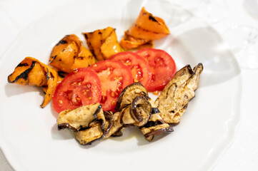 Italian cuisine, colorful grilled vegetables eggplants, pumpkins served with fresh tomatoes .