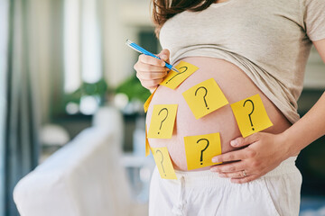 Guess the sex. Shot of a woman with sticky notes with question marks on her pregnant belly.