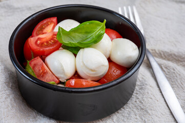 Tasty caprese salad with cherry tomatoes, white mozzarella cheese and green basil leaves