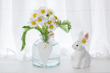 Easter wooden handmade rabbit with a bouquet of daisies and a white wooden heart