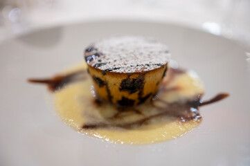 Tasty Italian dessert, small hot cake with chocolate and white gravy on white plate