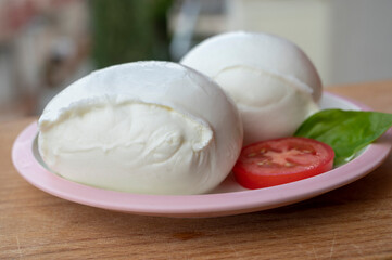 White ball of Italian soft cheese Mozzarella di Bufala Campana with fresh green basil and red tomato