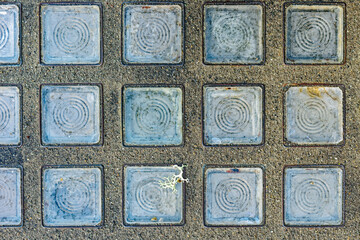 A series of clear glass tiles inlaid in a concrete floor