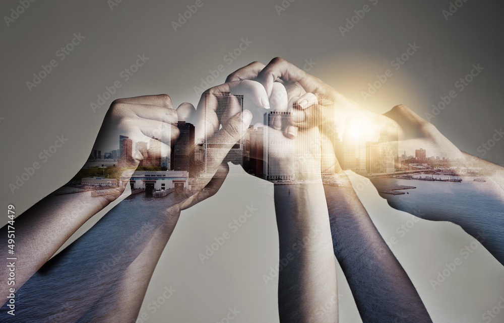Poster our unity is our strength. shot of a city superimposed over an unidentifiable business team holding 