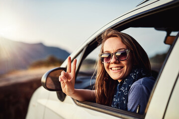 Take it easy. Portrait of a young woman showing a piece sign while sitting in her car.