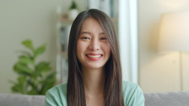 Portrait of young Asian woman look at camera and smile at home.