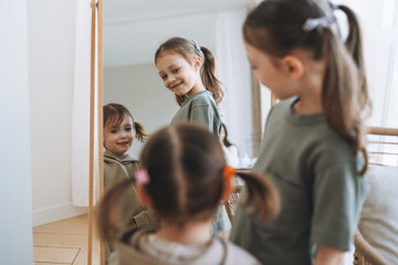 Cute little sisters girls looking on mirror at the home