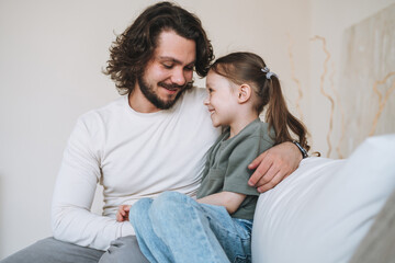Young happy family with father and daughter on sofa in cozy home, father day