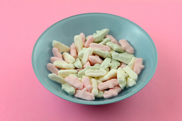 Pink and white candy pieces in blue dessert bowl on pink background