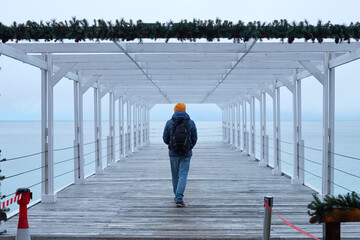 A man in winter clothes by the sea looks into the distance. The concept of travel, winter holidays. Front view.