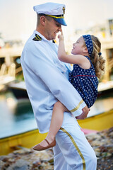 Got your nose. Shot of a father in a navy uniform bonding with his little girl on the dock.