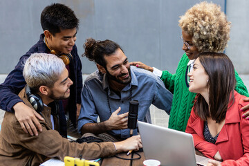 Happy teen multiracial diverse student friends doing homework together while using laptop and smiling at the street. Education concept