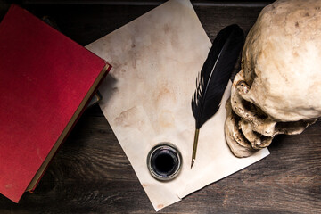 books, human skull, pen and paper on rustic wood