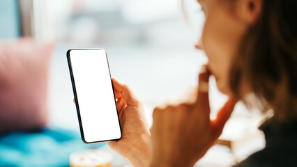 Woman in cafe holding blank white phone. Mockup empty background