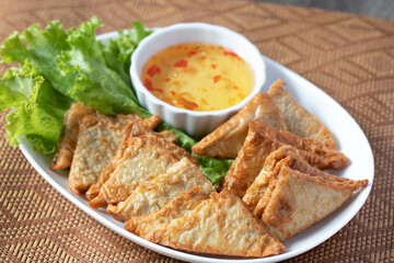 Triangular fried tofu eating with spicy dipping sauce, sweet and spicy