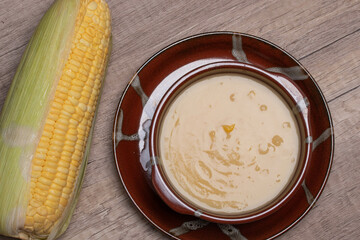 Sweet corn soup in a ceramic cup on wooden background.