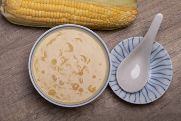 Sweet corn soup in a ceramic cup on wooden background.