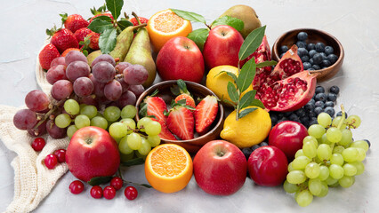 Assortment of colorful ripe tropical fruits on light gray background.