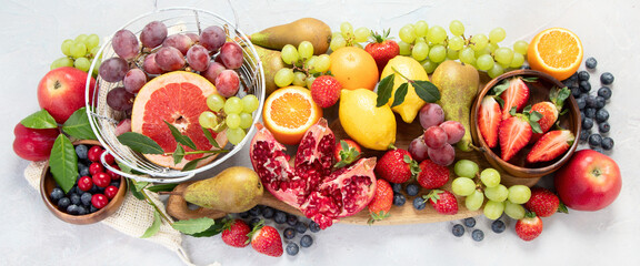 Assortment of colorful ripe tropical fruits on light gray background.