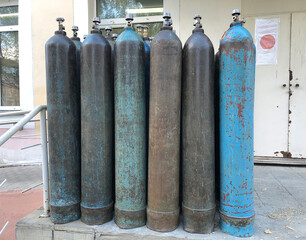 A lot of blue oxygen cylinders are standing near the building on the porch