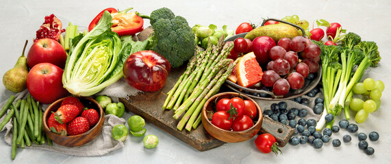 Delicious raw fruits and vegetables on light background.