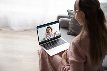 Shoulder rear view happy young pregnant woman holding laptop on laps, consulting with female obstetrician gynecologist online by video call, regular prenatal screening, telemedicine concept.