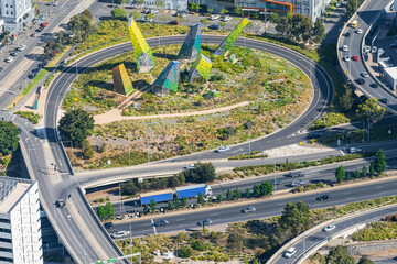 Looking down on a busy freeway with off and on ramps encircling a modern metal sculpture