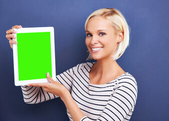 So many apps to choose from. Studio shot of a young woman holding up a digital tablet with a chroma key screen.