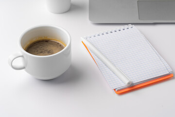 Office desk with laptop, blank notebook and coffee cup