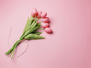 Bouquet of tulip flowers with colored eggs instead of buds on pastel pink background. Creative Easter holiday concept. Natural surreal traditional holiday greeting card, poster or banner. Flat lay.