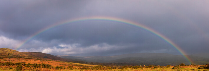 Vibrant rainbows over Combestone Tor on Dartmoor Devon in the west country of England UK