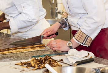 Pâtissière découpant un gâteau en gros plan. Ecole de cuisine et de pâtisserie.