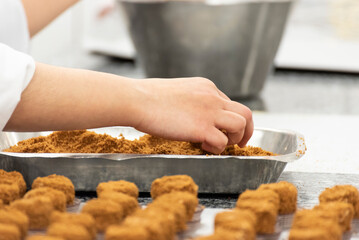 Gros plan sur une main entrain d'envelopper des boulettes de pâtes en pâtisserie pour confectionner des gâteaux amuse bouche.