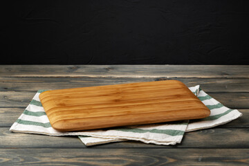 Wooden board with kitchen napkin on dark wooden table - Powered by Adobe
