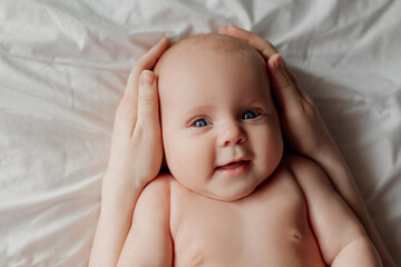 mother holds the baby's head in her hands. cute sweet newborn baby