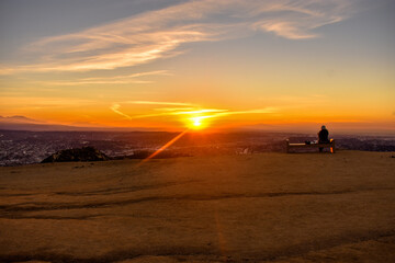 Fototapeta premium Person watching sunrise sitting on bench