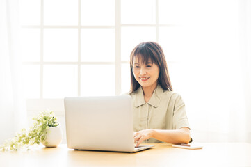 パジャマでテレワークするミドル世代の女性（笑顔）
