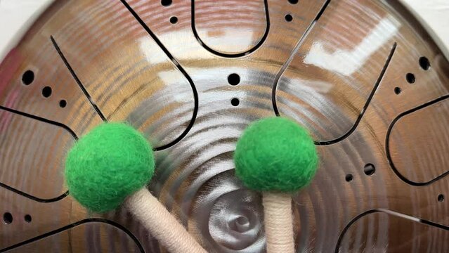 A musical instrument, a glucophone, a drum with a metal tongue on a wooden background. A modern musical instrument with wooden sticks. A tool for meditation, relaxation, with a deep magical sound