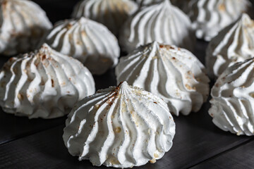 Close-up Meringues prinkled with nuts on dark wooden rustic table. low key, side view, selective focus.