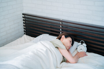 目覚まし時計で起きる女性（遅刻）
