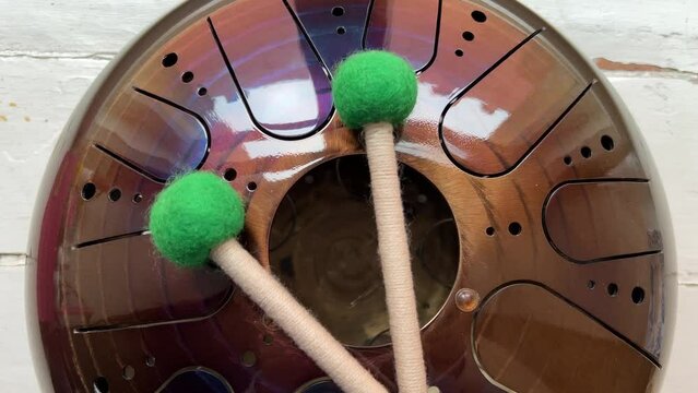 A musical instrument, a glucophone, a drum with a metal tongue on a wooden background. A modern musical instrument with wooden sticks. A tool for meditation, relaxation, with a deep magical sound
