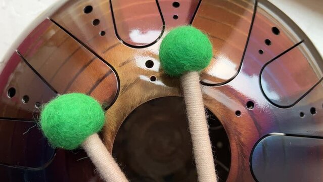 A musical instrument, a glucophone, a drum with a metal tongue on a wooden background. A modern musical instrument with wooden sticks. A tool for meditation, relaxation, with a deep magical sound