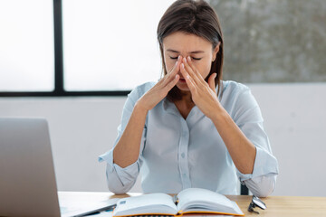 Portrait of tired stressed caucasian woman having headache feeling sick sitting at the workplace in...