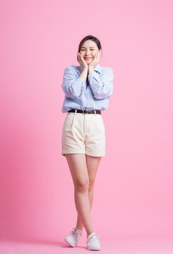 Full length image of young Asian woman posing on pink background