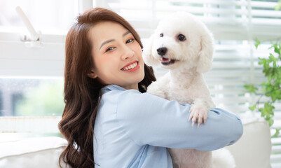 Young Asian woman playing with dog at home