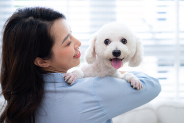 Young Asian woman playing with dog at home