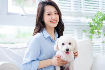 Young Asian woman playing with dog at home