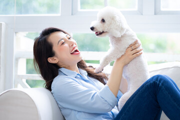 Young Asian woman playing with dog at home