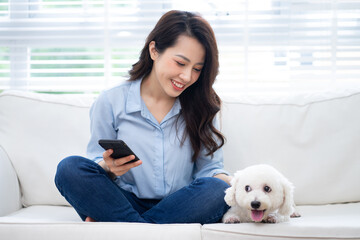 Young Asian woman playing with dog at home